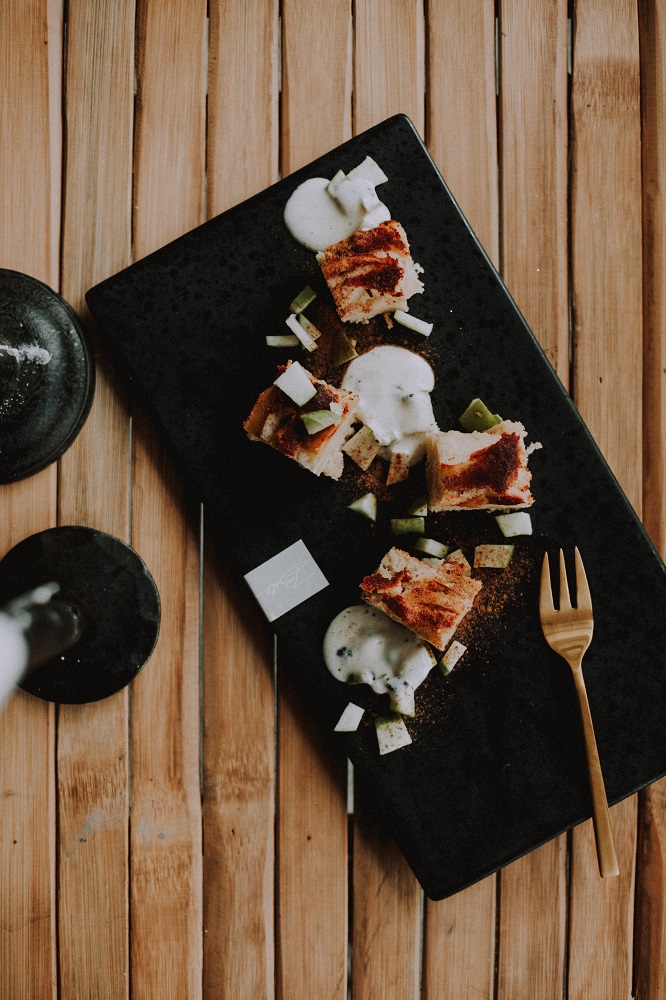 Un postre sobre el plato negro que esta en la mesa