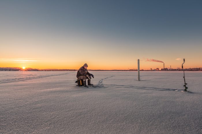El hombre de los países nórdicos sobre el lago helado pescando en el invierno