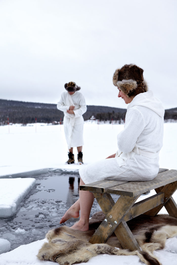 Una mujer y un hombre alrededor de un agujero en el lago helado en el invierno en los países nórdicos