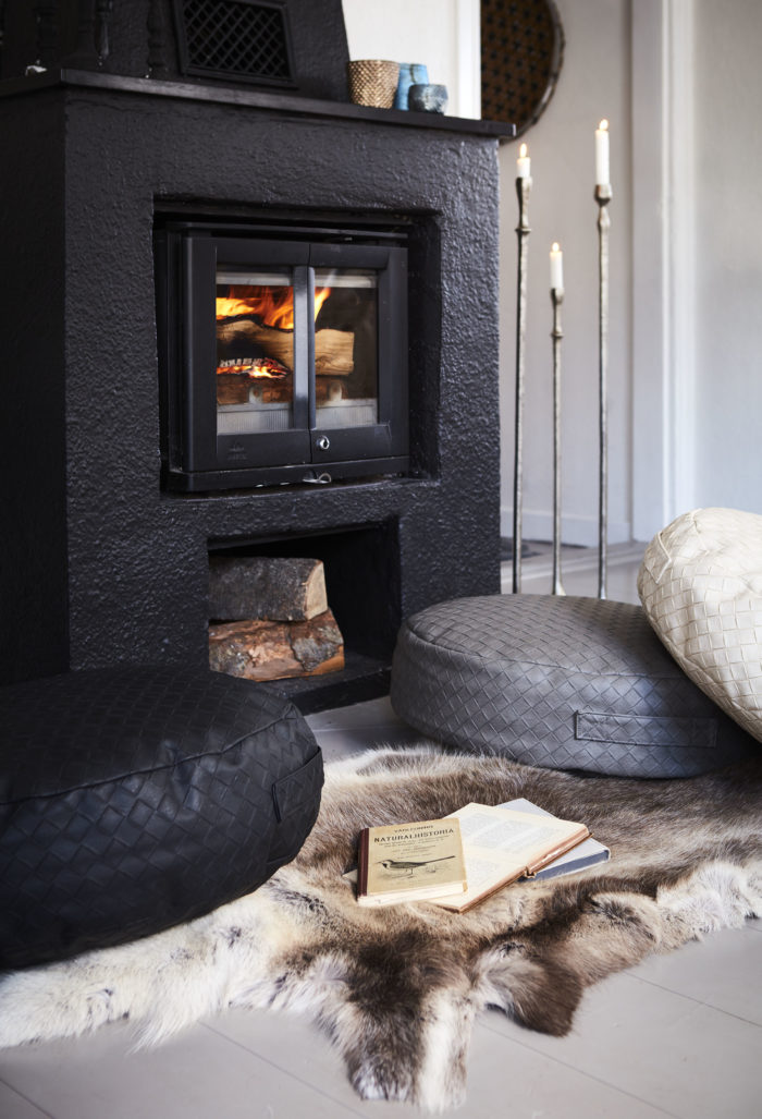 Libros y almohadas en el suelo delante de una chimenea